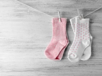 Baby socks hanging on the clothesline on wooden background