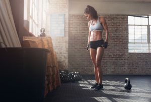 Fit and young woman standing in crossfit gym