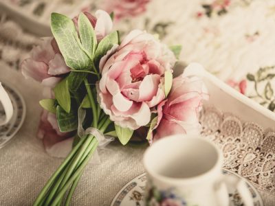 retro styled photo of pink flowers lying on tray with teacups