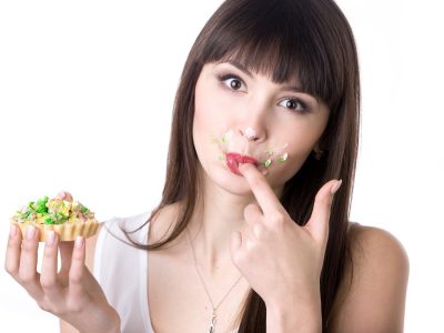 Woman licking her fingers while eating cake