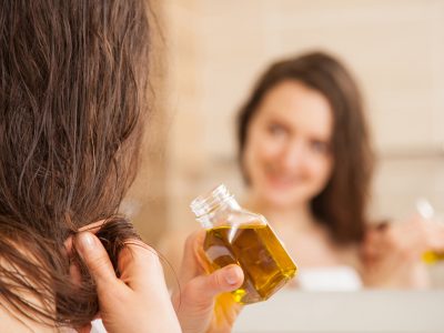 Young woman applying oil mask to hair tips